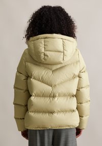 Gepolsterte Pufferjacke in hellgelb mit Kapuze, Chevron-Steppung und glatter Oberfläche. Hergestellt aus strapazierfähigem synthetischem Material.