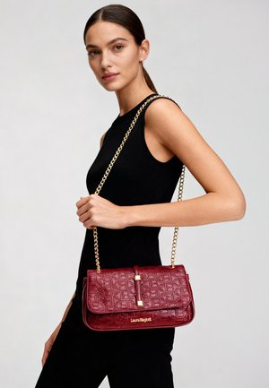 Borsa a tracolla bordeaux con finitura testurizzata, tracolla a catena dorata e dettagli con logo. Forma rettangolare con design a patta pieghevole.