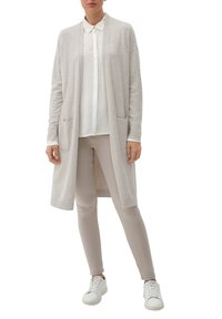 Ljusgrå stickad cardigan med öppen front, två fickor, kombinerad med en vit blus och beige byxor, samt vita sneakers.
