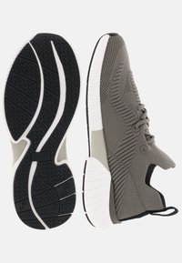 Chaussures de sport en tissu tricoté gris; tiges texturées avec design à lacets; semelle en caoutchouc noire avec accents blancs; construction légère.
