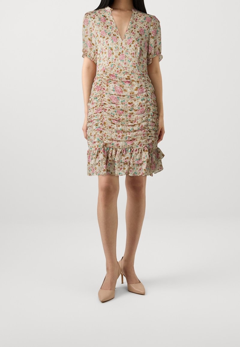 Robe fleurie avec un décolleté en V, des manches courtes et une texture froncée. Elle présente un ourlet volanté et des couleurs douces, principalement roses, beiges et vertes.
