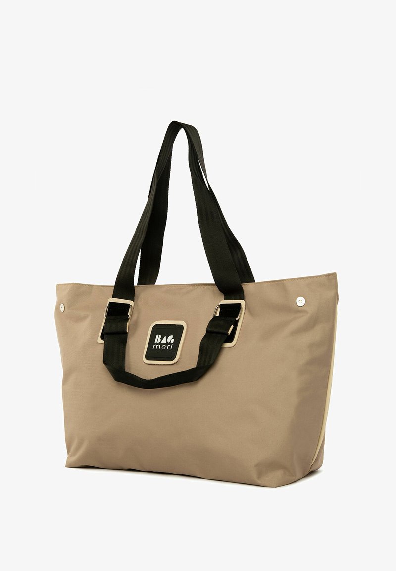 Bežinė rankinė su juodais rankenomis ir juodu logotipo pavidalu, pasižyminti tvirtu audiniu, stačiakampiu pavidalu ir sidabrinėmis mygtukų detalėmis.