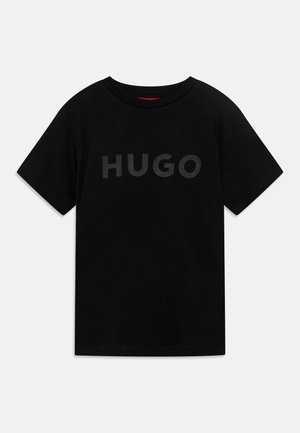 Camiseta de algodón negra con un gran logo "HUGO" negro mate en el pecho. Tiene un cuello redondo clásico y mangas cortas.
