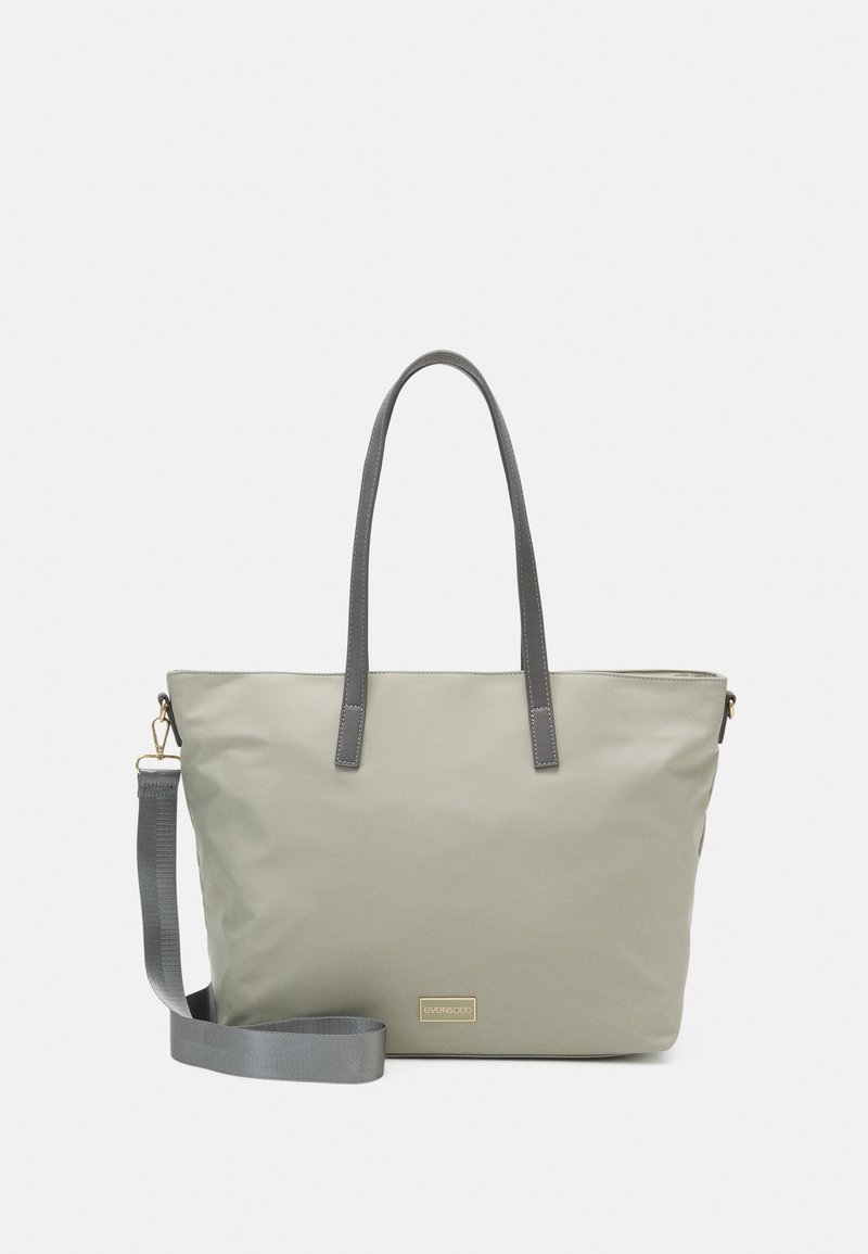 Gray tote bag made of smooth fabric with two long handles and a detachable strap. Features a gold brand logo on the front.