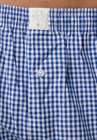 Modré a bílé kostkované boxerky vyrobené z bavlny. Mají elastický pas a jeden knoflík vpředu. Štítek na pase.