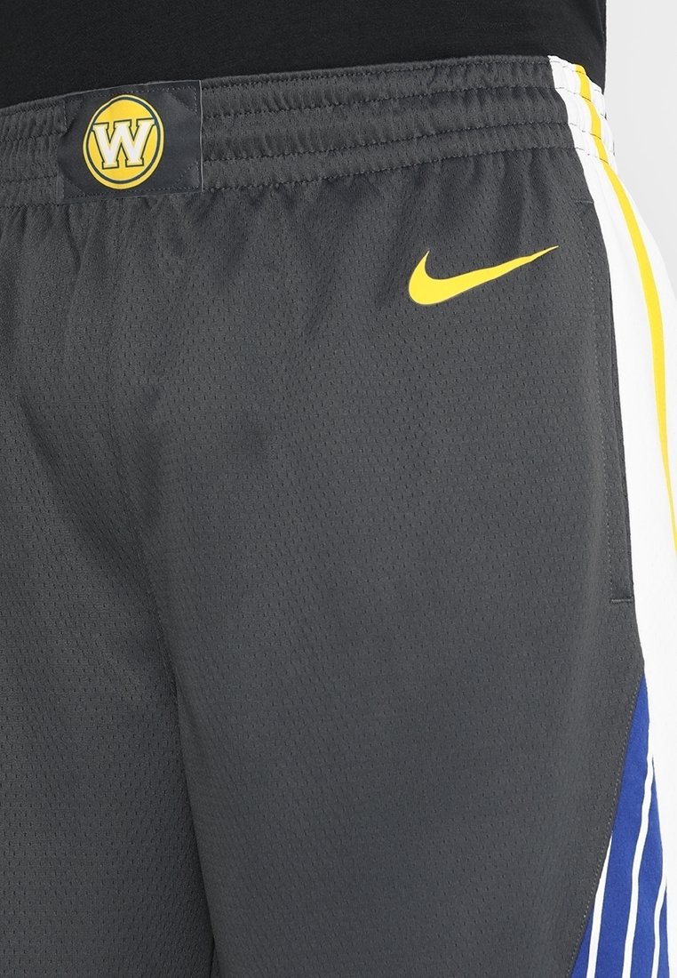 Shorts d'athlétisme gris en tissu mesh avec un logo Nike jaune, un patch des Warriors sur la taille, et des accents blancs et bleus sur les côtés.