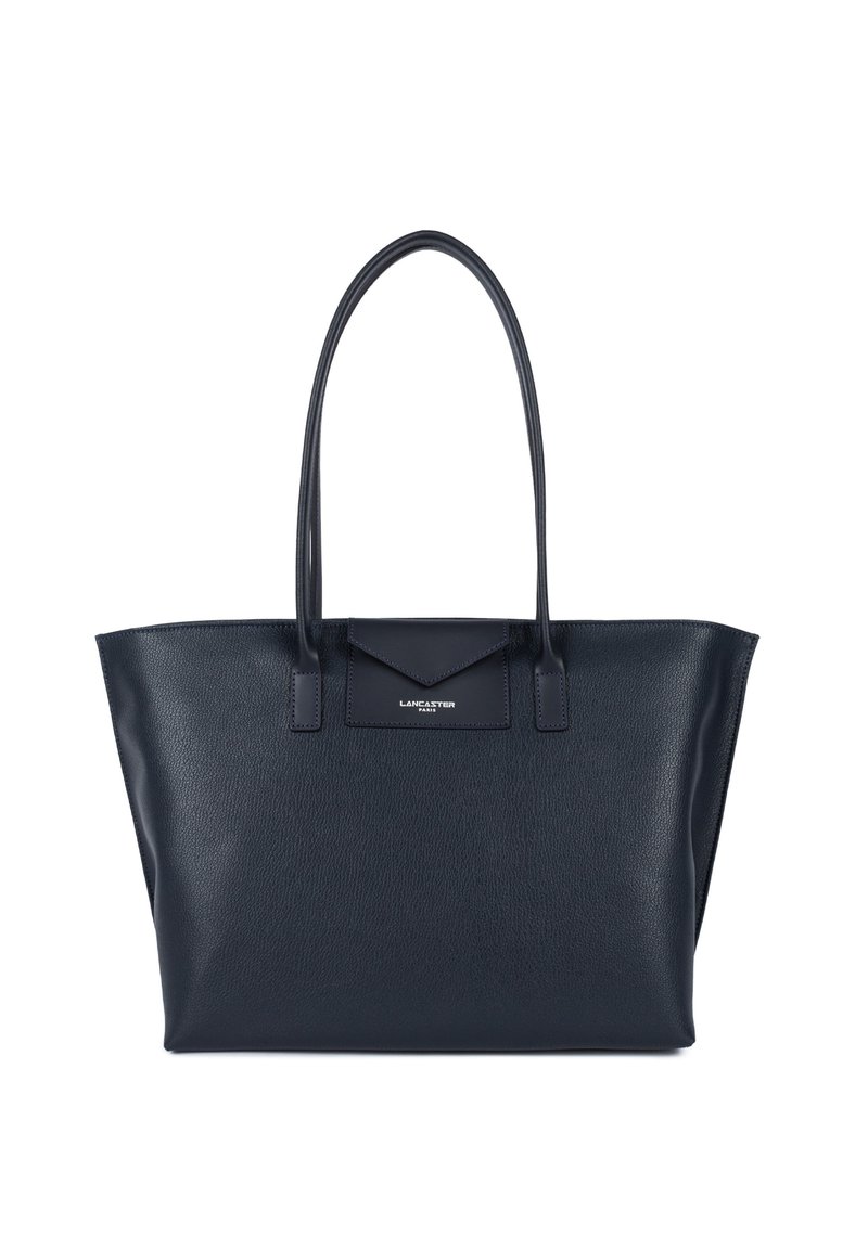 Sac en cuir navy avec de longues poignées, de forme rectangulaire et un fini texturé. Présente un logo subtil sur le rabat de la poche avant.