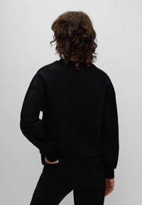 Schwarzes Sweatshirt mit lässiger Passform, gerippten Bündchen und Saum. Hergestellt aus weichem Stoff, mit rundem Ausschnitt und lässiger Silhouette.