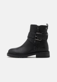 Black leather ankle boot with a rounded toe, side zipper, and a decorative buckle strap. Textured surface and a chunky heel.