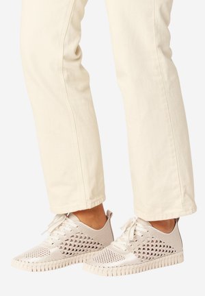 Lyse beige vævede sneakers med snørebånd, båret med cremefarvede bukser, der viser et afslappet og åndbart skodesign.