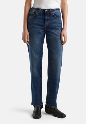 Jean droit en denim bleu avec cinq poches, rivets en cuivre et braguette à boutons. La texture du tissu est lisse avec un léger délavage sur les jambes.