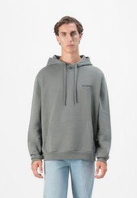 Grå hettegenser med snorhette og kengurulomme. Stoffet har en jevn tekstur, og har et lite logo på brystet.
