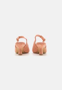 Chaussures à talons hauts en suède rose avec une bride de cheville et un talon épais. Texture lisse avec un design à bout rond et un minimalisme dans les détails.