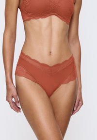 Roodbruine lingerie set bevat een kant-bra met gegolfde randen en bijpassende low-rise slipjes met kanten en gladde stofpanelen.