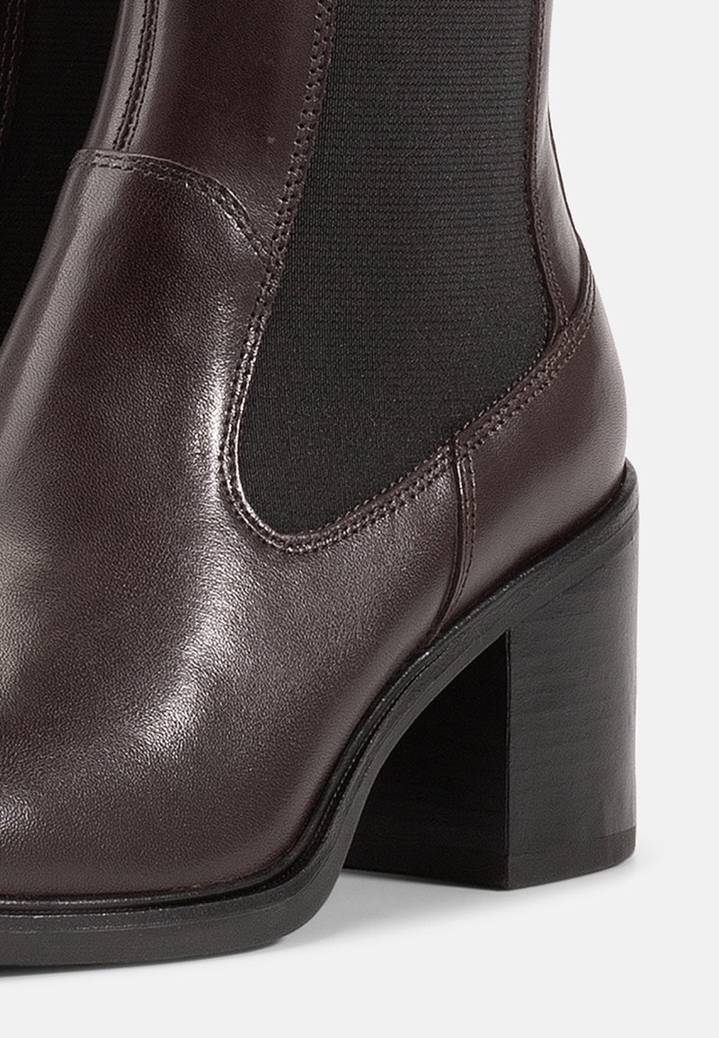 Stivaletto in pelle marrone con finitura liscia, pannelli laterali elasticizzati, punta rotonda e tacco spesso nero.