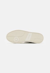 Sole della sneaker Levi's, in gomma testurizzata, di colore beige con motivi circolari e lineari, con logo del marchio al centro.