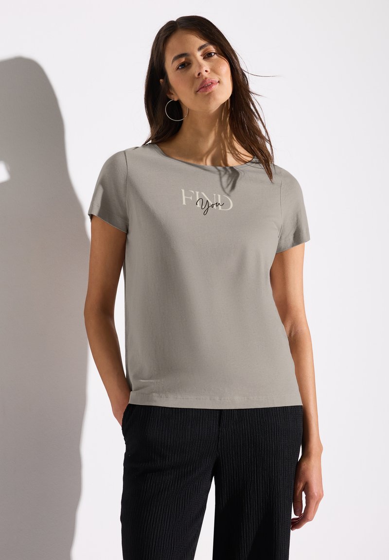 T-shirt gris à manches courtes avec le texte « FIND You », col rond, texture douce, associé à un pantalon noir texturé.