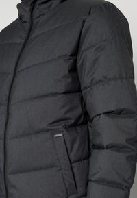 Grå dunjakke med lynlåslukning, quiltet design, sidelommer og et tekstureret stof. Har en høj krave for ekstra varme.