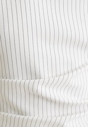 Biała tkanina z cienkimi pionowymi niebieskimi paskami, gładka w dotyku z subtelnymi zmarszczkami. Materiał wydaje się lekki i lekko elastyczny.