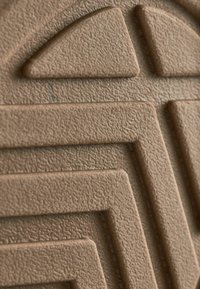 Matériau texturé marron avec un motif géométrique embossé de lignes entrelacées et de triangles, évoquant un effet tridimensionnel.