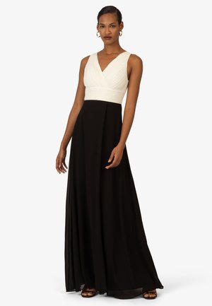 Schwarzes und weißes Kleid mit einem taillierten Oberteil, das ein gefälteltes weißes Oberteil und einen fließenden schwarzen Rock präsentiert. Bodenlanger, ärmelloser Schnitt.