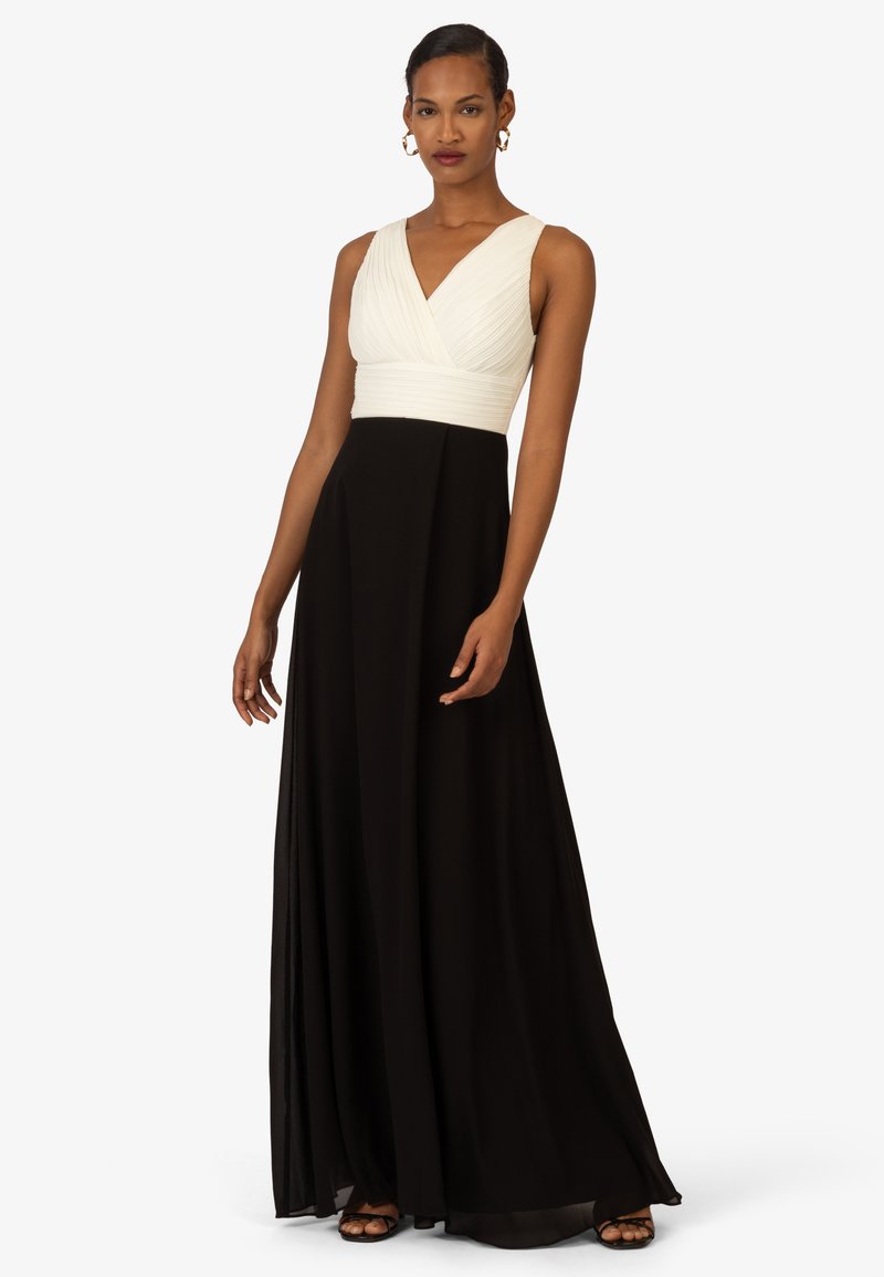 Schwarzes und weißes Kleid mit einem taillierten Oberteil, das ein gefälteltes weißes Oberteil und einen fließenden schwarzen Rock präsentiert. Bodenlanger, ärmelloser Schnitt.