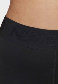 I leggings sportivi neri presentano una vasta cintura elastica impresso con il nome del marchio. Il tessuto è morbido ed elastico con cuciture piatte.