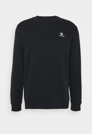 Sort sweatshirt lavet af bomuld, med rund hals, lange ærmer og et lille hvidt Converse-logo på brystet. Glat tekstur.