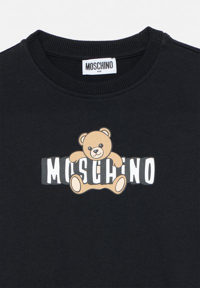 Maglietta nera per bambini con una grafica di un orsetto che tiene lettere bianche a blocchi che formano la parola "MOSCHINO" sul petto.