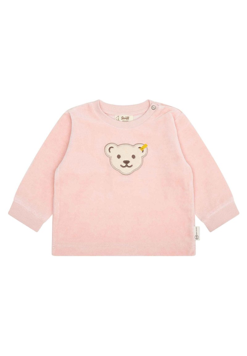 Camisa de manga larga rosa claro en tejido suave con un aplique de cara de oso y un acento amarillo, cuello redondo y broche en el hombro para facilitar el vestido.