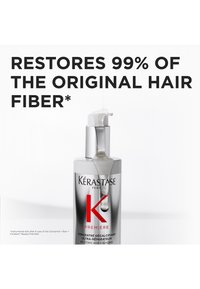 Kérastase hårbehandling i en silverfärgad flaska med en vit pump, texturerad etikett, rött 'K' och vätska som droppar från munstycket.