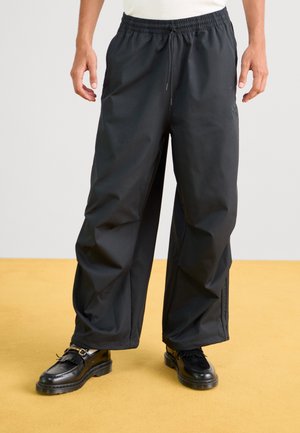 Zwarte, losvallende broek met een elastische tailleband en trekkoord, met een gladde textuur en zonder zichtbare patronen of hardware details.