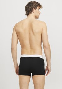 Schwarze Boxershorts mit einem weißen elastischen Bund, die eine glatte Textur und eine enge Passform aufweisen, aus einer Rückansicht gezeigt.