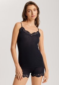Navy ribbed camisole with adjustable straps, featuring a scalloped lace trim at the neckline and matching lace-accented shorts.