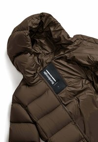 Giacca a vento marrone con design trapuntato, esterno lucido, cappuccio ampio e etichetta all'interno con texture a rete.