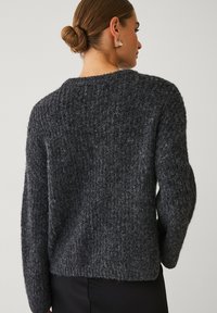 Chunky gebreide trui in donkergrijs met een gestructureerd oppervlak, ronde halslijn en een relaxed fit. Bevat lange mouwen en een ongeversierde achterkant.