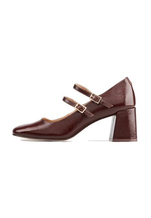Chaussure Mary Jane en cuir verni marron avec deux brides à boucles dorées et un talon bloc sur fond blanc.