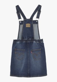 Abito in denim blu scuro con bretelle regolabili, elastico in vita e due tasche posteriori con il caratteristico dettaglio di cucitura di Levi's.