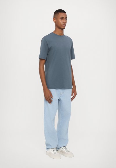 Grå kortærmet t-shirt med rund halsudskæring, parret med lyseblå brede jeans og hvide sneakers. Minimalistisk design og blød tekstur.