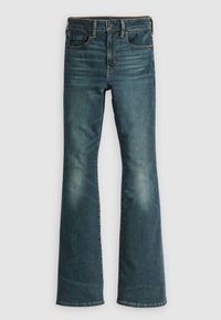 Jeans de denim acampanados en azul profundo con un acabado desgastado. Presentan una cintura alta, un diseño estándar de cinco bolsillos y un cierre de botón metálico.