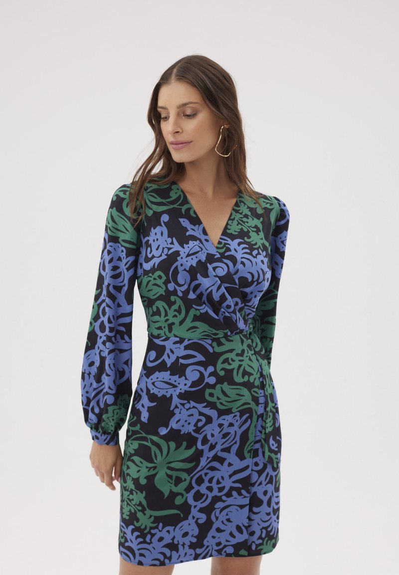 Sukienka kopertowa z czarnym tłem, ozdobiona niebieskimi i zielonymi wirującymi wzorami kwiatowymi. Długie bufiaste rękawy oraz głęboki dekolt w kształcie litery V. Gładka faktura materiału.