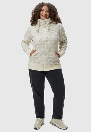 Light beige zip-up hoodie with textured pattern, hood, and pockets. Paired with dark jeans and light-colored sneakers.