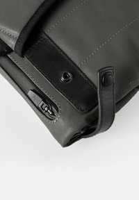 Schwarze Stofftasche mit glatter Textur, mit einem Lederakzent, Druckknopfverschluss und einem Reißverschlussfach an der Seite.