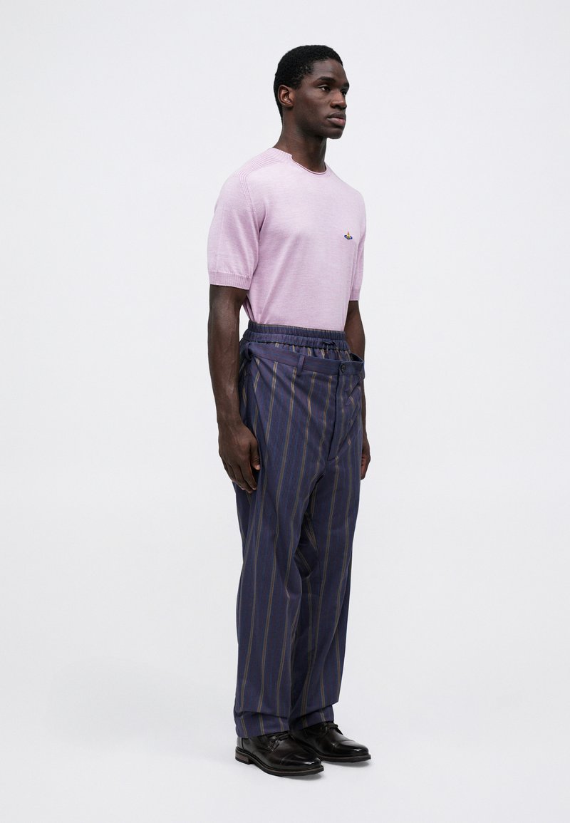 Maglione corto a maniche corte di colore rosa chiaro con costine sottili e dettagli ricamati; pantaloni a righe blu navy con vita elasticizzata; scarpe nere.