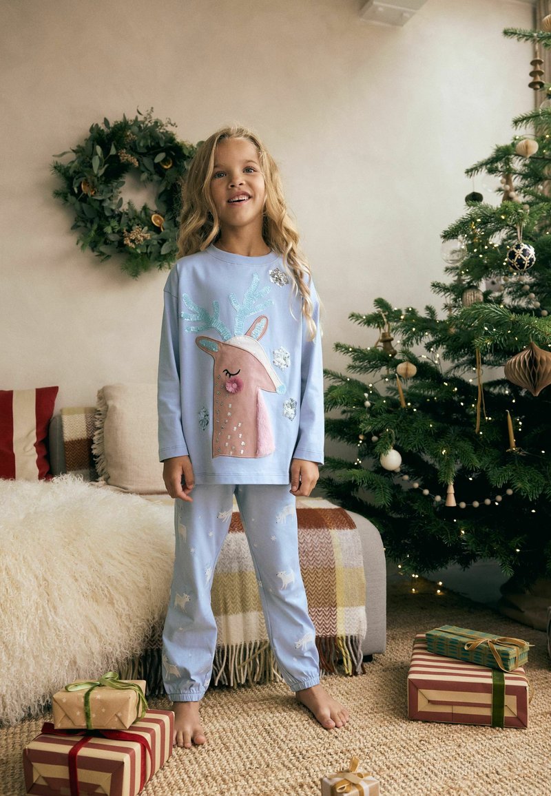 Light blue pajama set featuring a reindeer design with sequins and ears on the shirt, and patterned pants with small unicorns.