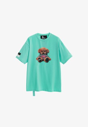 Camiseta turquesa de manga corta con un oso de peluche con capucha gris impreso en el frente y un pequeño parche en blanco y negro en la manga.