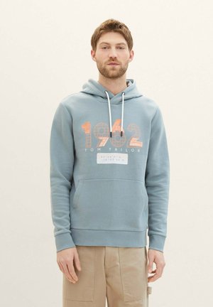 Hoodie in lichtblauw, met grote oranje "1962" grafiek en de tekst "TOM TAILOR", voorzien van een voorzak en een capuchon met trekkoord.