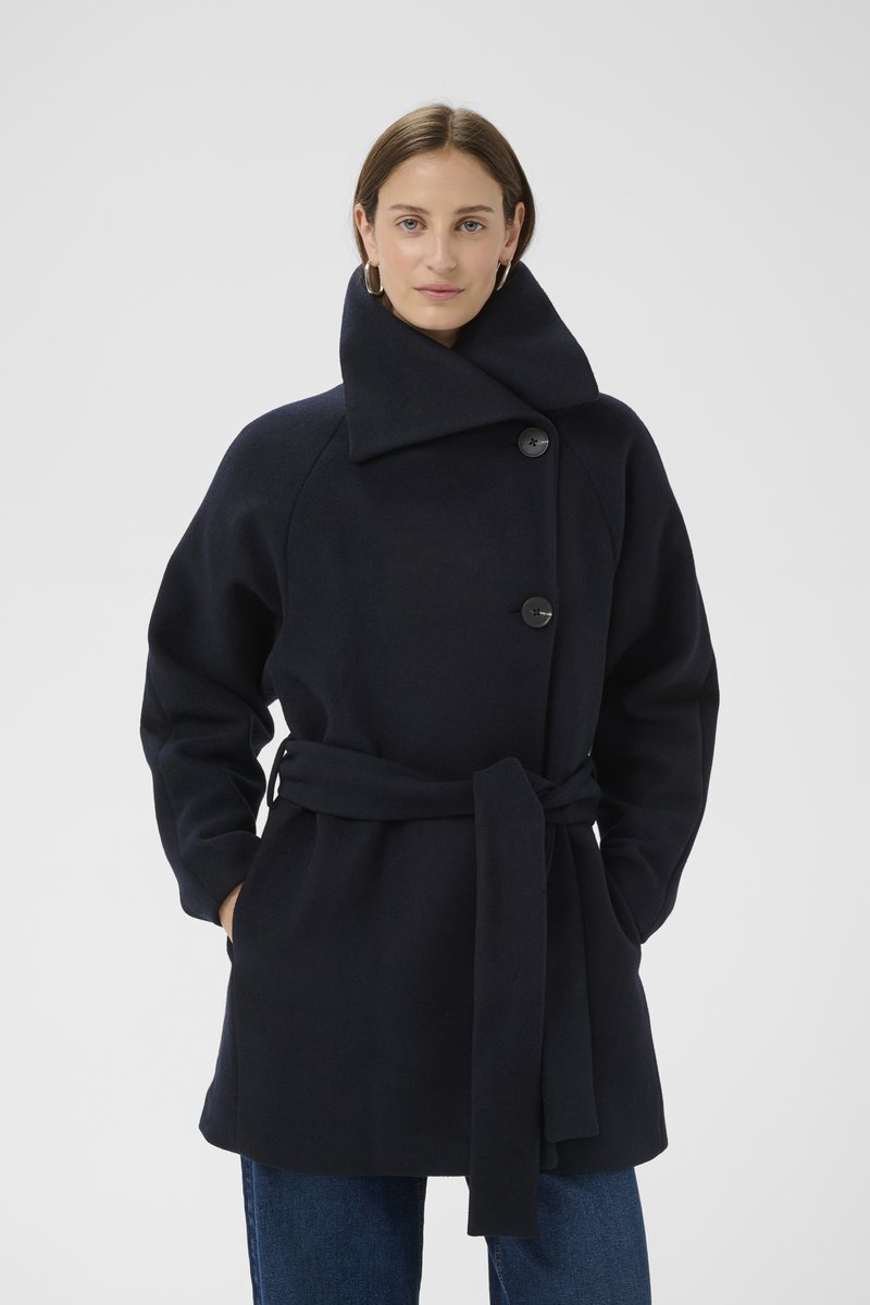 Tengerészkék gyapjúkeverék kabát magas gallérral, elöl gombokkal és derékrésznél övvel, laza sziluettel és oldalzsebekkel.