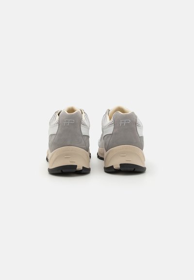 Chaussures de sport en cuir gris et blanc avec des accents en mesh, col rembourré et semelle en caoutchouc beige. Comprend un détail de logo sur le talon.