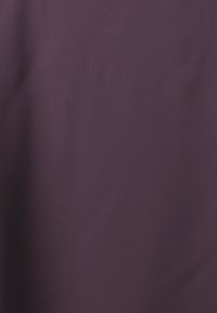 Tessuto viola con una texture liscia e opaca. La superficie appare uniforme senza motivi o decorazioni visibili.